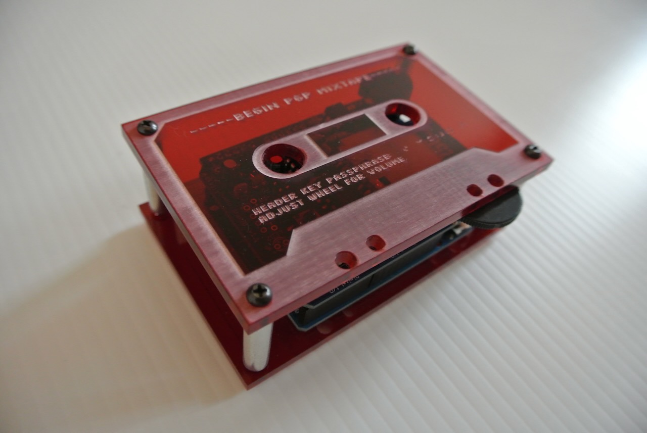 An Arduino microcontroller and music player circuit board in a transparent red transparent acrylic enclosure laser-etched to look like a cassette tape.